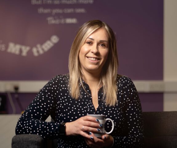 Michelle smiling holding a cup of coffee